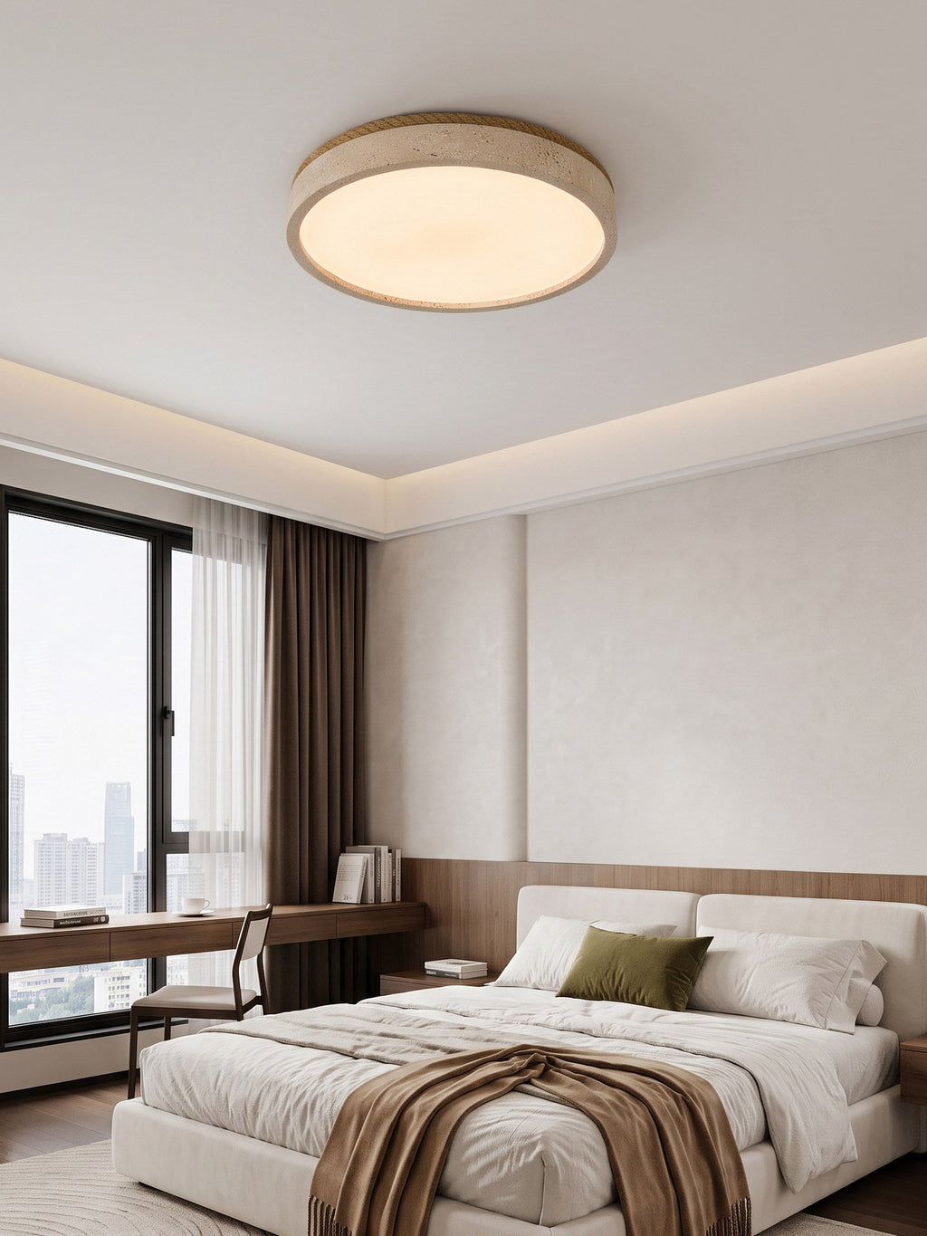 This round Clérachic ceiling light glows above a bed with an olive cushion, facing a floor-to-ceiling window and city view.