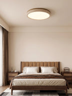 This Clérachic flush mount light glows warm above a bed with a tufted headboard and a patterned rug underfoot.