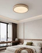 Warm light from this round Clérachic ceiling fixture fills a bedroom with a city skyline through the floor-to-ceiling window.