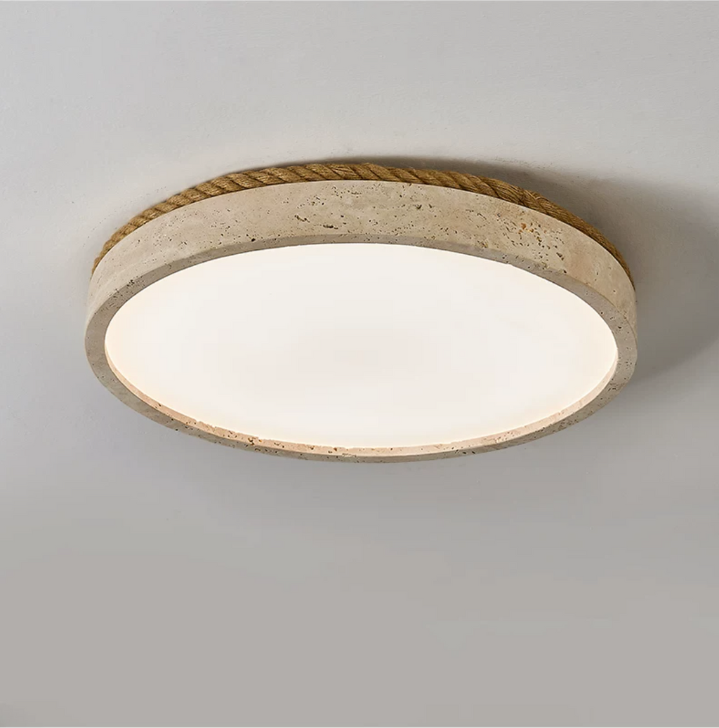 Close angled view of this round Clérachic ceiling light in yellow travertine, its wound jute rope rim against a grey backdrop.