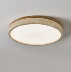 Close angled view of this round Clérachic ceiling light in yellow travertine, its wound jute rope rim against a grey backdrop.