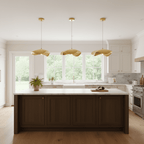 White kitchen walls frame a dark wood island lit by three hammered brass shades from Clérachic.