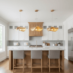 Three lit hammered brass pendants from Clérachic hang over a white kitchen island with grey stools.