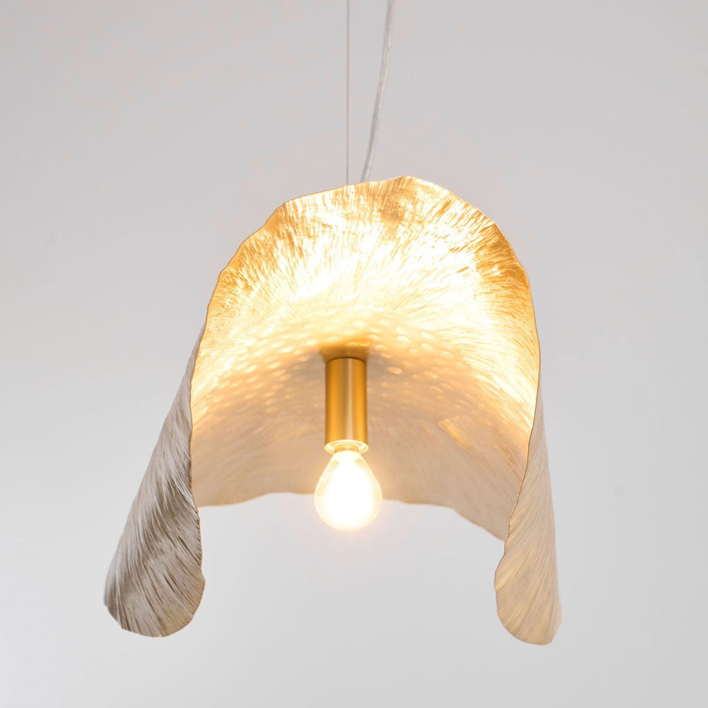 Seen from below, this Clérachic shade's lit bulb sits inside its flower-like brass folds.