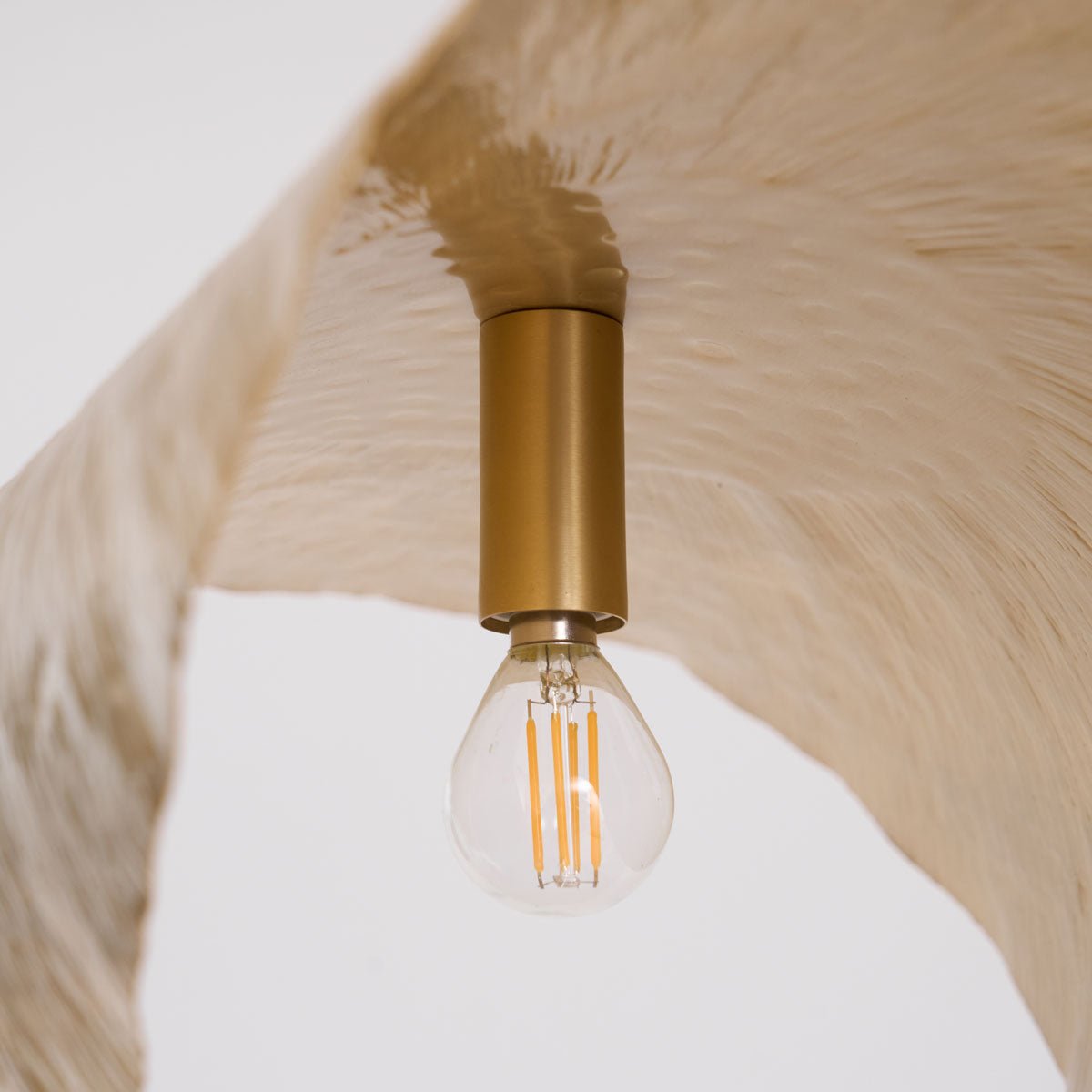 A close view shows the brass socket and filament bulb inside this Clérachic pendant's shade.