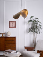 This Clérachic pendant hangs small and lit in a room with a wood cabinet and tall plant.