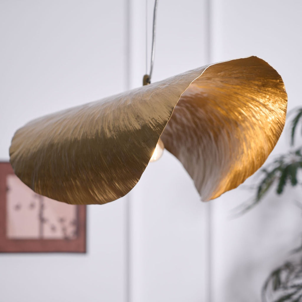 A closer view shows this Clérachic shade lit gold beside the same framed print and plant.