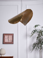 This Clérachic hammered brass shade hangs unlit again beside the framed print and potted plant.
