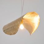 The bulb glows between the folded brass lobes of this Clérachic pendant, shown at an angle.