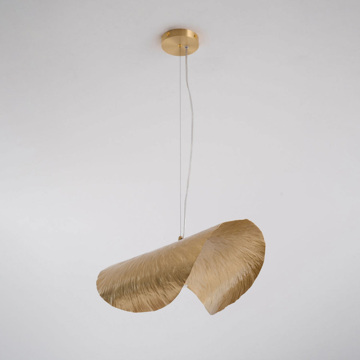 Unlit and on a longer cord, this Clérachic hammered brass shade hangs from its brass canopy.