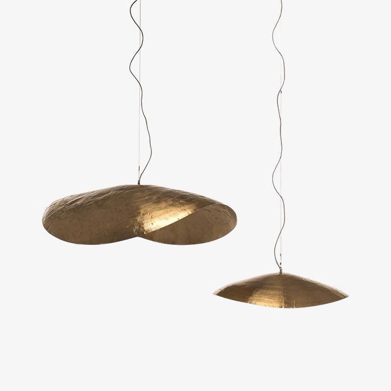 Two unlit Clérachic hammered brass shades hang at different heights against plain white.