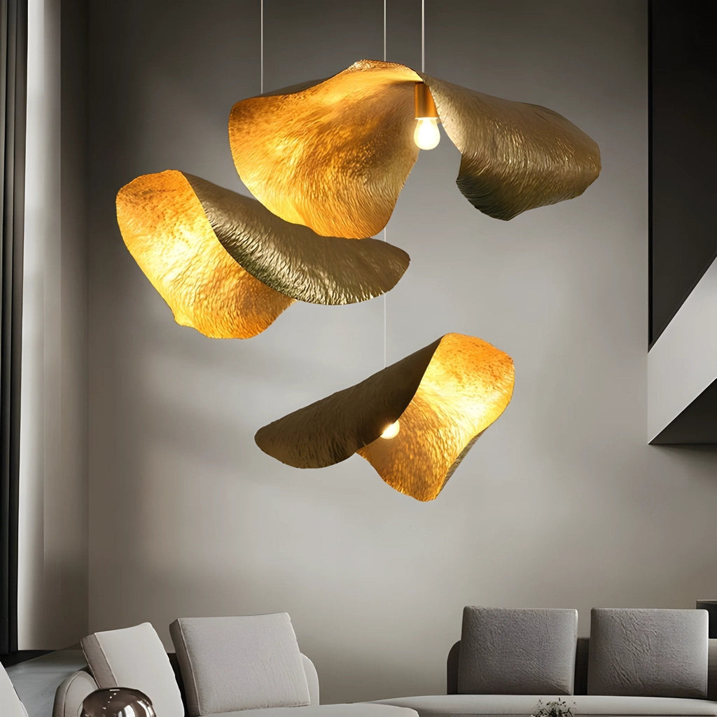 A cluster of hammered brass shades from Clérachic glows gold above a grey-walled living room sofa.