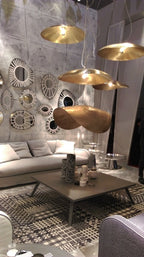 A cluster of Clérachic hammered brass shades hangs before a wall of decorative mirrors.
