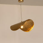 Mounted on a visible cord, this Clérachic pendant glows gold against a plain wall.