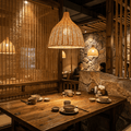 The bamboo bell pendant lit over a reclaimed wood table in a stone-and-bamboo dining room
