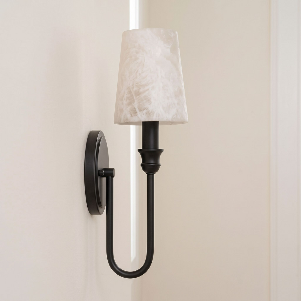 This Clérachic sconce in black hardware shows its U-loop arm from the side, alabaster shade against a plain wall.