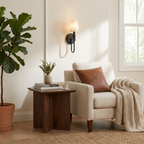 Beside a window and a fiddle-leaf fig, this Clérachic sconce in black hardware lights an armchair reading corner.