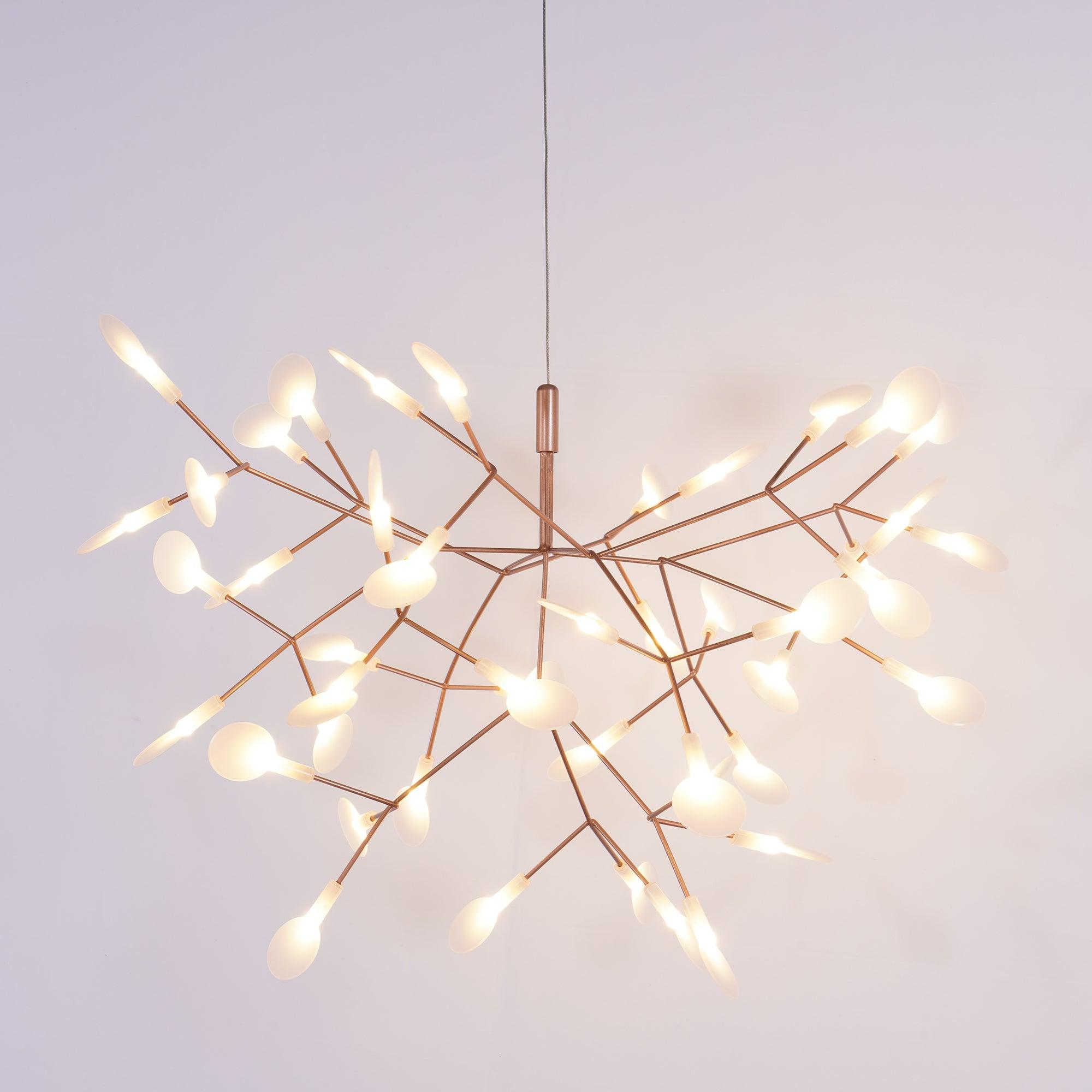 Rose gold firefly chandelier lit as a sculptural centrepiece