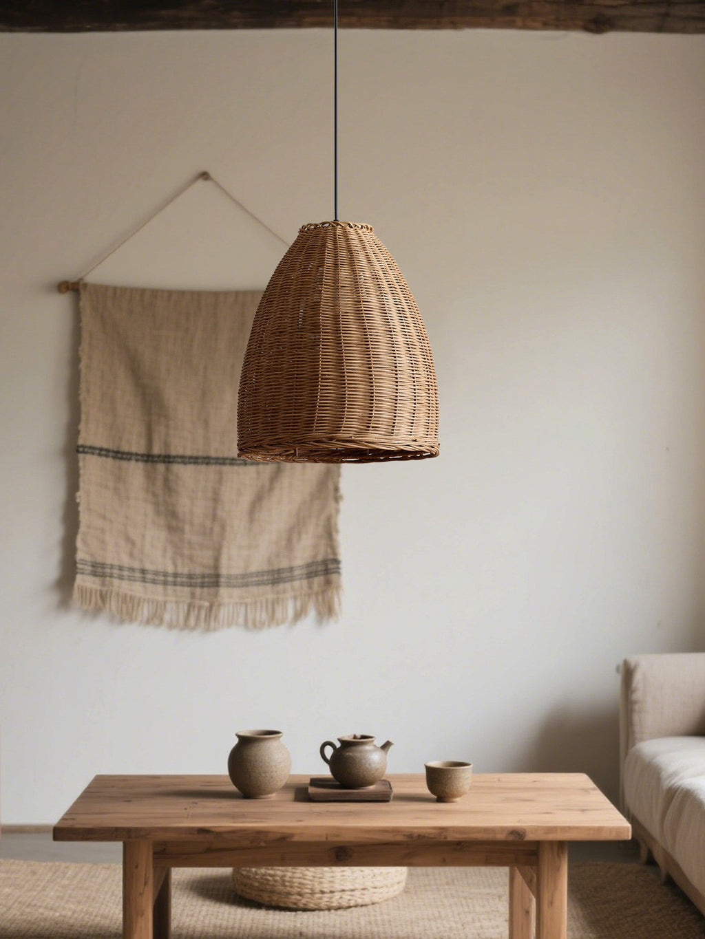 A woven textile hanging and pottery sit near a wood coffee table beneath this rattan Clérachic pendant.