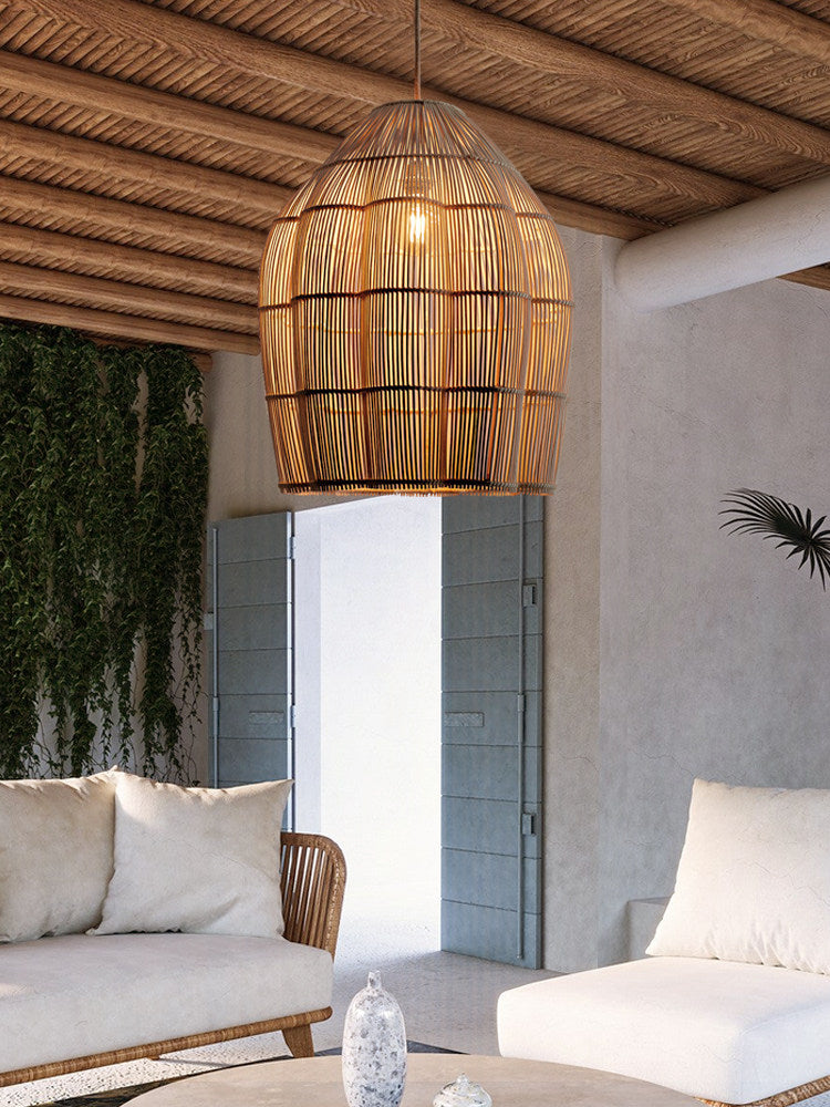 Under a wood-beamed ceiling, this lit Clérachic pendant hangs in an open room with trailing greenery.