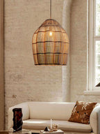Lit warmly beneath a tall brick wall, this Clérachic pendant glows above a cream sofa with a patterned cushion.