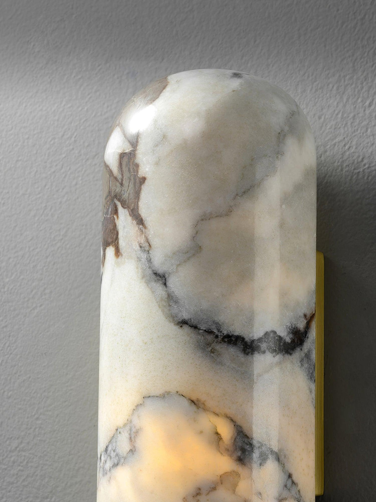 Clérachic marble cylinder wall light in close-up, showing the veined marble texture and its gold-edged brass mount.