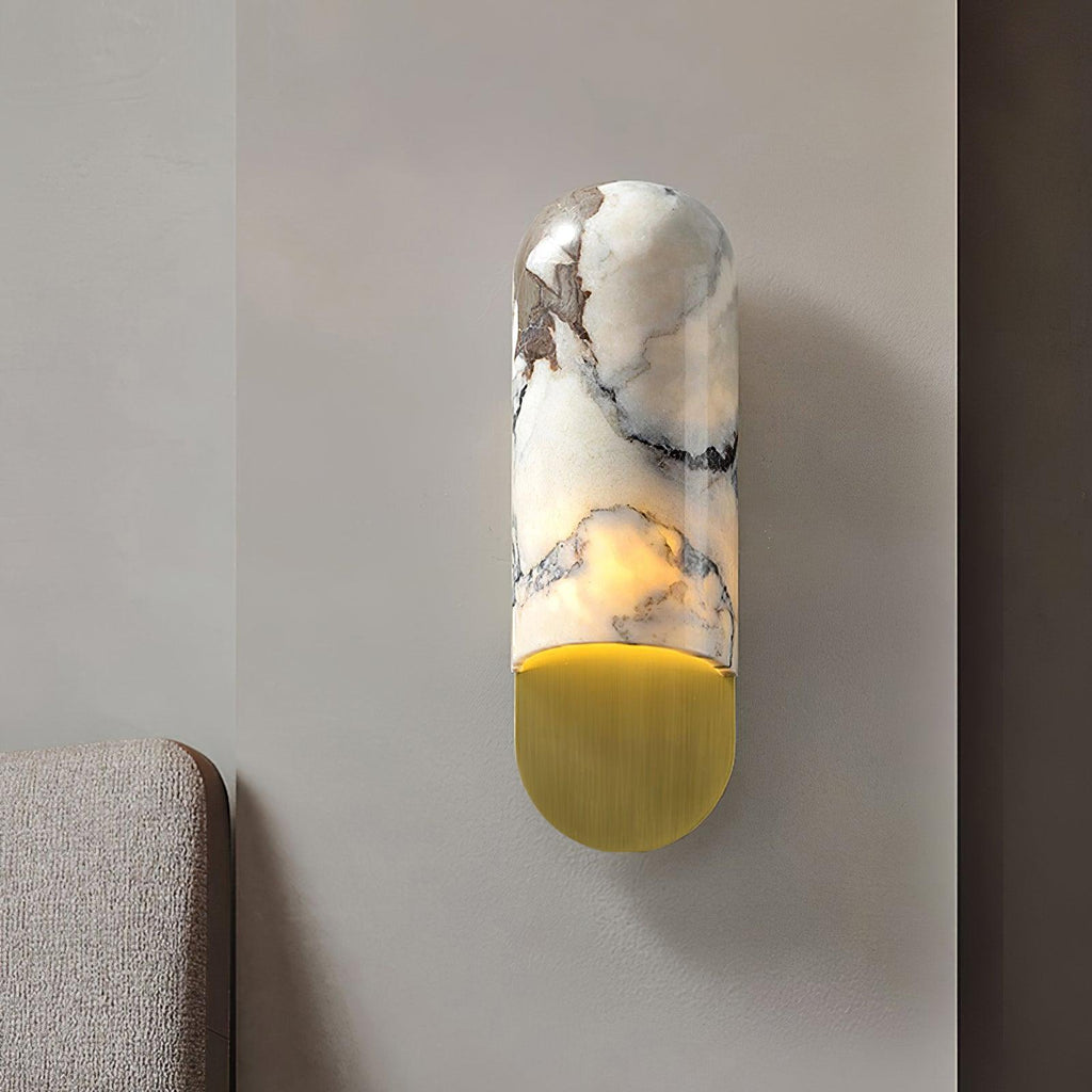 Clérachic marble cylinder wall light glowing warm in a room corner, beside the edge of an upholstered headboard.