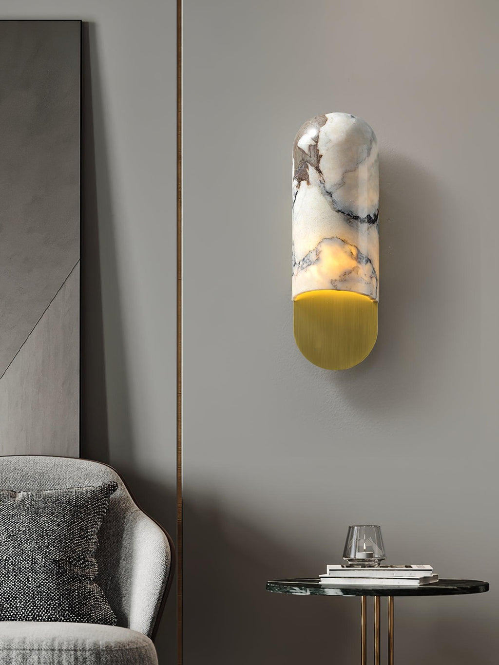 Warm light spills from the Clérachic marble cylinder wall light beside a mirrored panel, above a grey armchair and round side table.