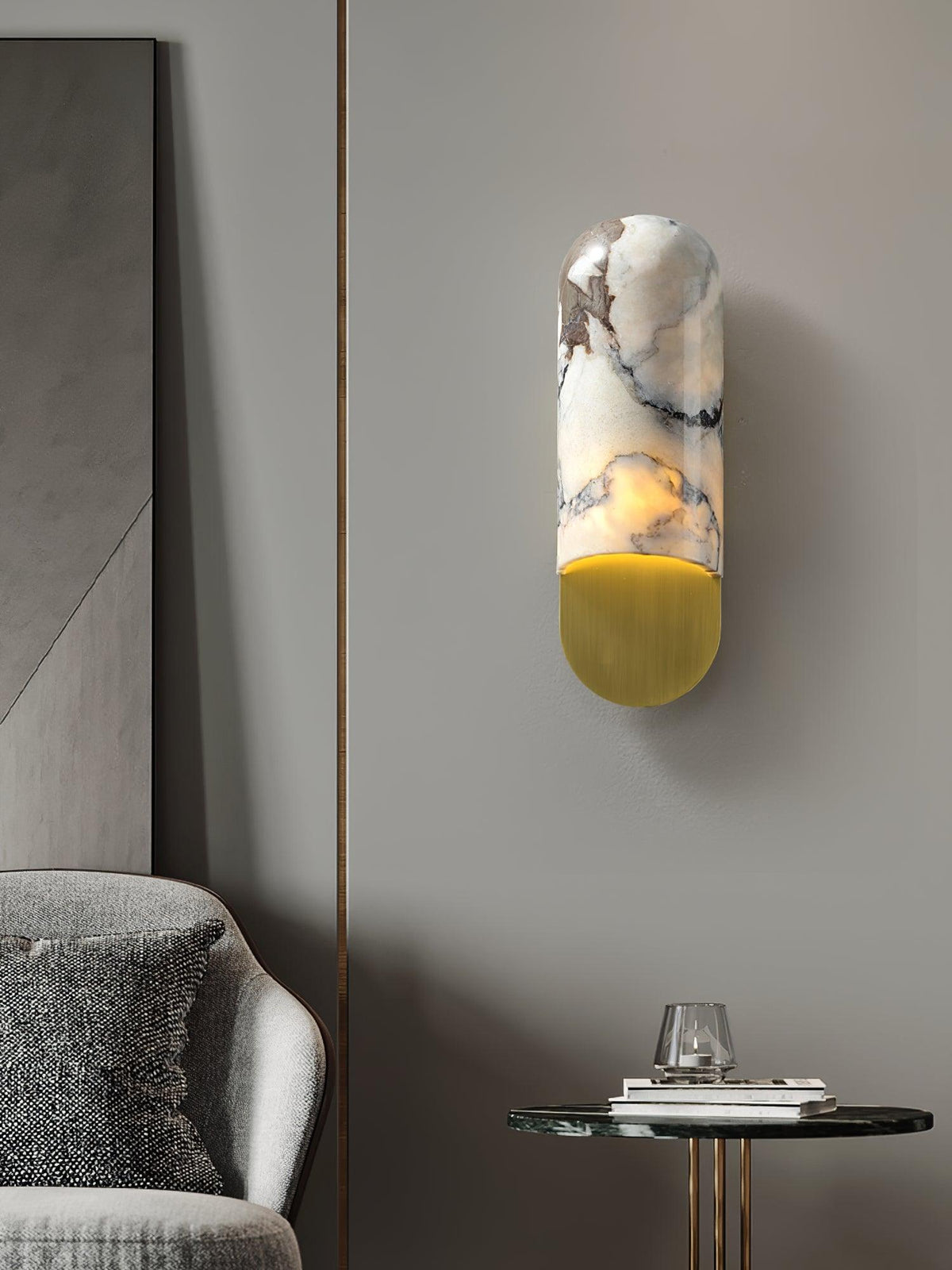 Warm light spills from the Clérachic marble cylinder wall light beside a mirrored panel, above a grey armchair and round side table.