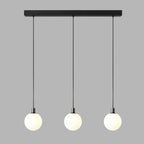 Three black-and-white Clérachic sphere pendants hang from a black bar at staggered heights on grey.