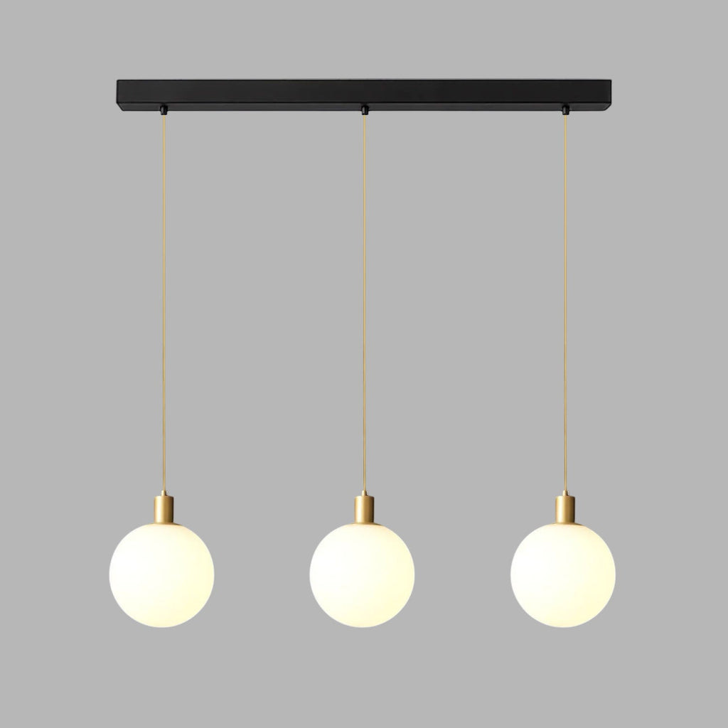 Three brass-and-white Clérachic sphere pendants hang from a black bar against plain grey.