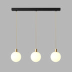 Three brass-and-white Clérachic sphere pendants hang from a black bar against plain grey.