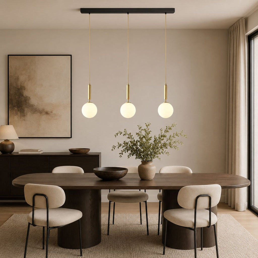 This Clérachic three-head pendant in brass and white hangs above a wood dining table.
