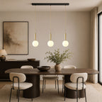 This Clérachic three-head pendant in brass and white hangs above a wood dining table.