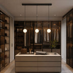 Three black-and-white Clérachic sphere pendants light a walk-in closet with glass-front cabinetry.