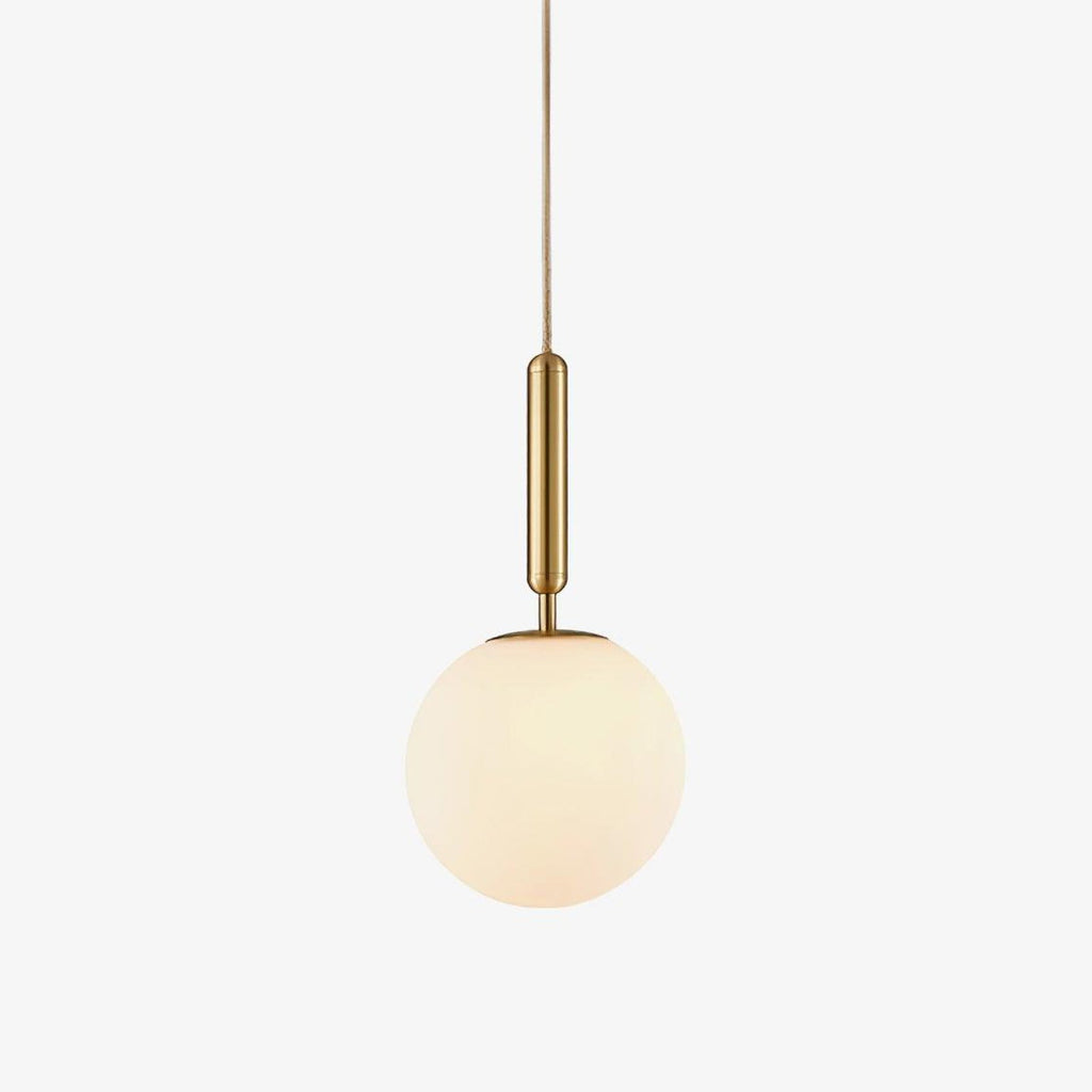 A single Clérachic sphere pendant in brass and white hangs lit against a plain white backdrop.