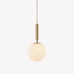 A single Clérachic sphere pendant in brass and white hangs lit against a plain white backdrop.