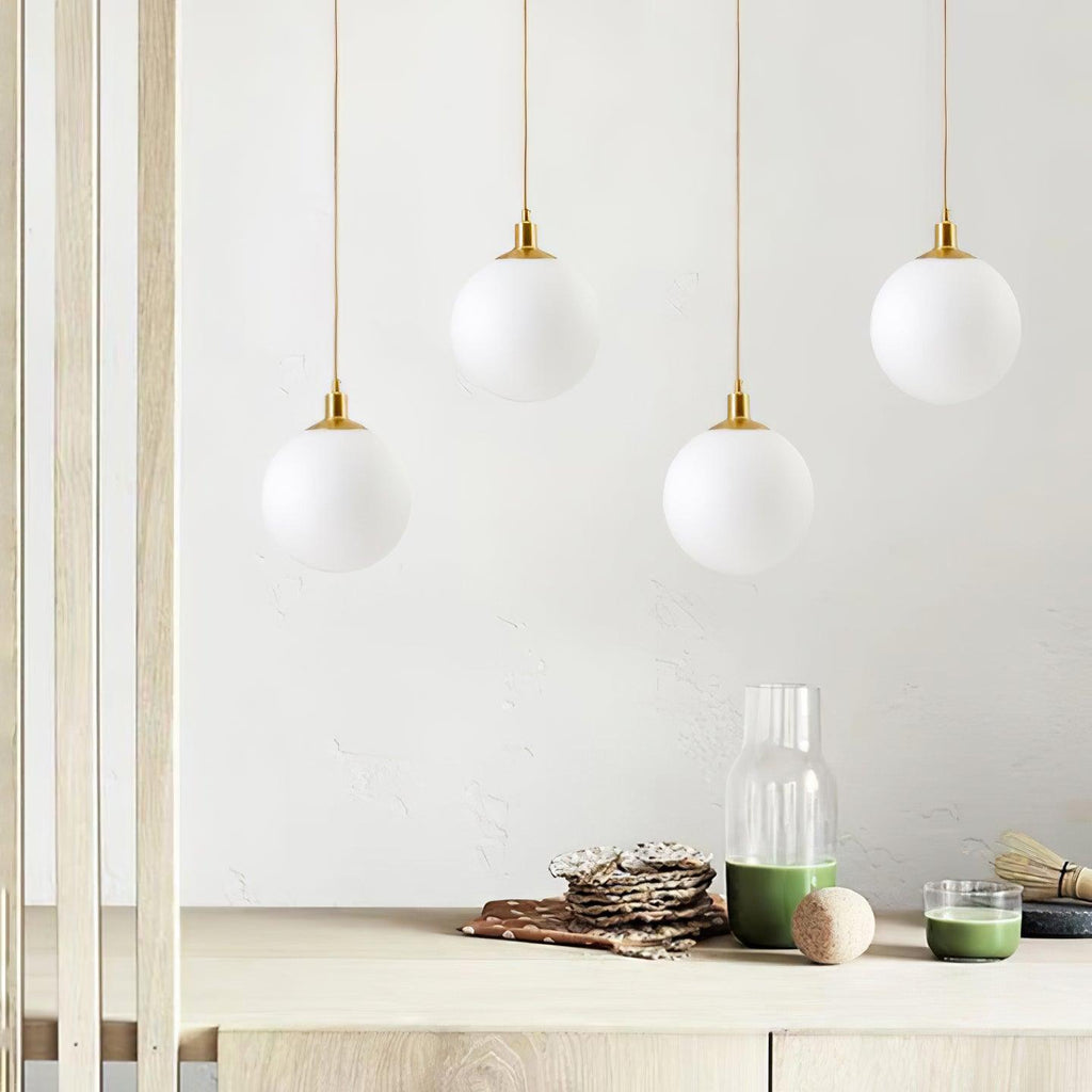 Several brass-and-white Clérachic sphere pendants hang at staggered heights above a wood console.