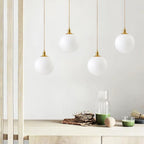 Several brass-and-white Clérachic sphere pendants hang at staggered heights above a wood console.