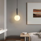 A single black-and-white Clérachic sphere pendant hangs beside a framed sunset print near a small table.