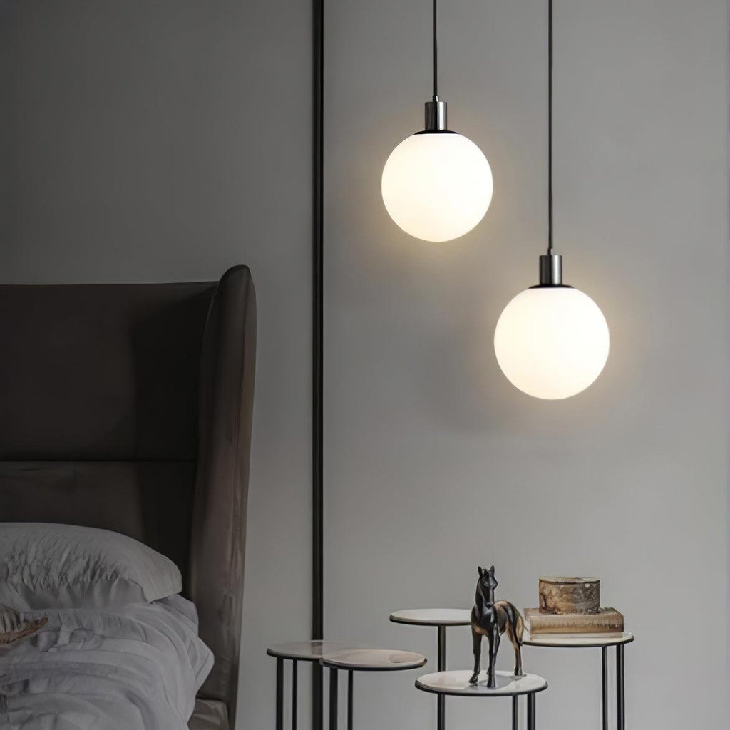Two black-and-white Clérachic sphere pendants hang at staggered heights near a side table with a horse figurine.