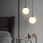 Two black-and-white Clérachic sphere pendants hang at staggered heights near a side table with a horse figurine.