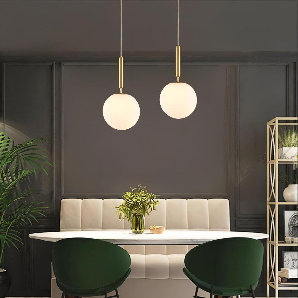 Two brass-and-white Clérachic sphere pendants hang above a banquette dining nook with green chairs.