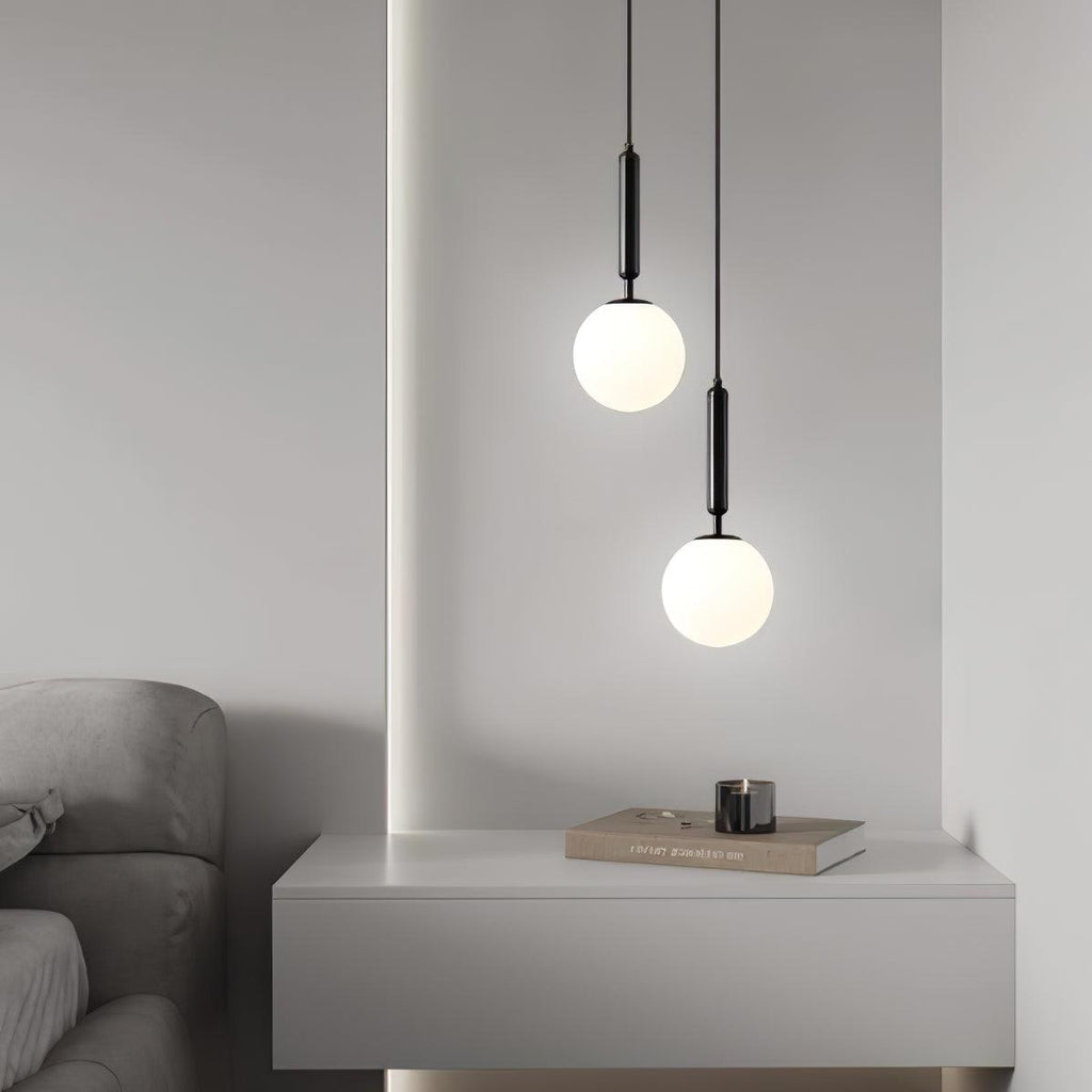 A console with a candle sits beneath two staggered black-and-white Clérachic sphere pendants.