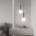 A console with a candle sits beneath two staggered black-and-white Clérachic sphere pendants.