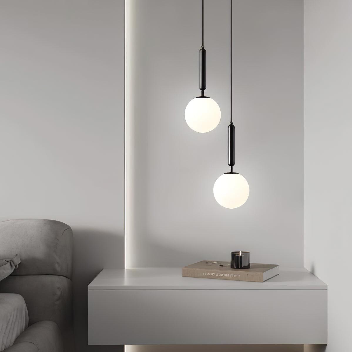 A console with a candle sits beneath two staggered black-and-white Clérachic sphere pendants.