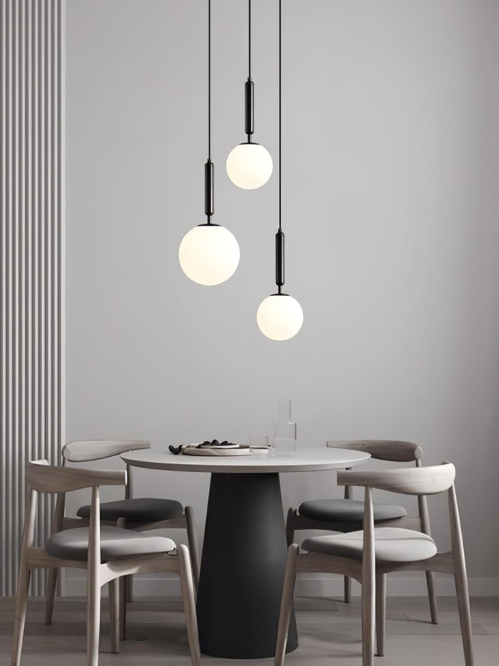 Three black-and-white Clérachic sphere pendants hang at staggered heights above a round dining table.
