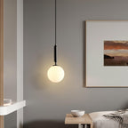 Seen closer, a single black-and-white Clérachic sphere pendant hangs beside a framed sunset print on grey.