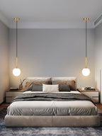 Two black-and-white Clérachic sphere pendants hang symmetrically above a low platform bed.