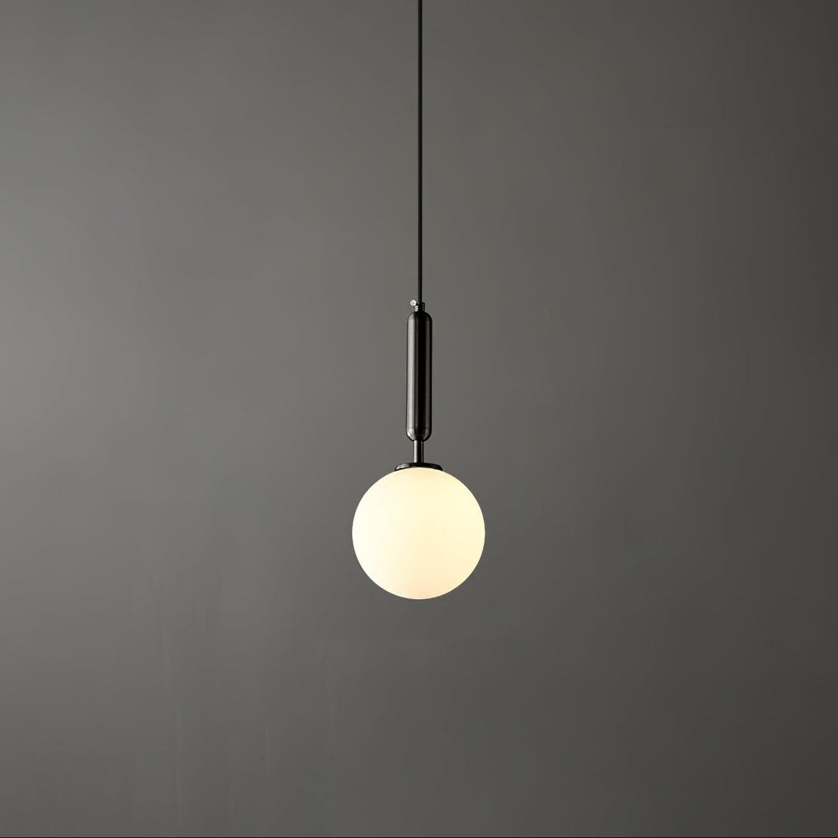 A single black-and-white Clérachic sphere pendant hangs lit against a dark grey studio backdrop.